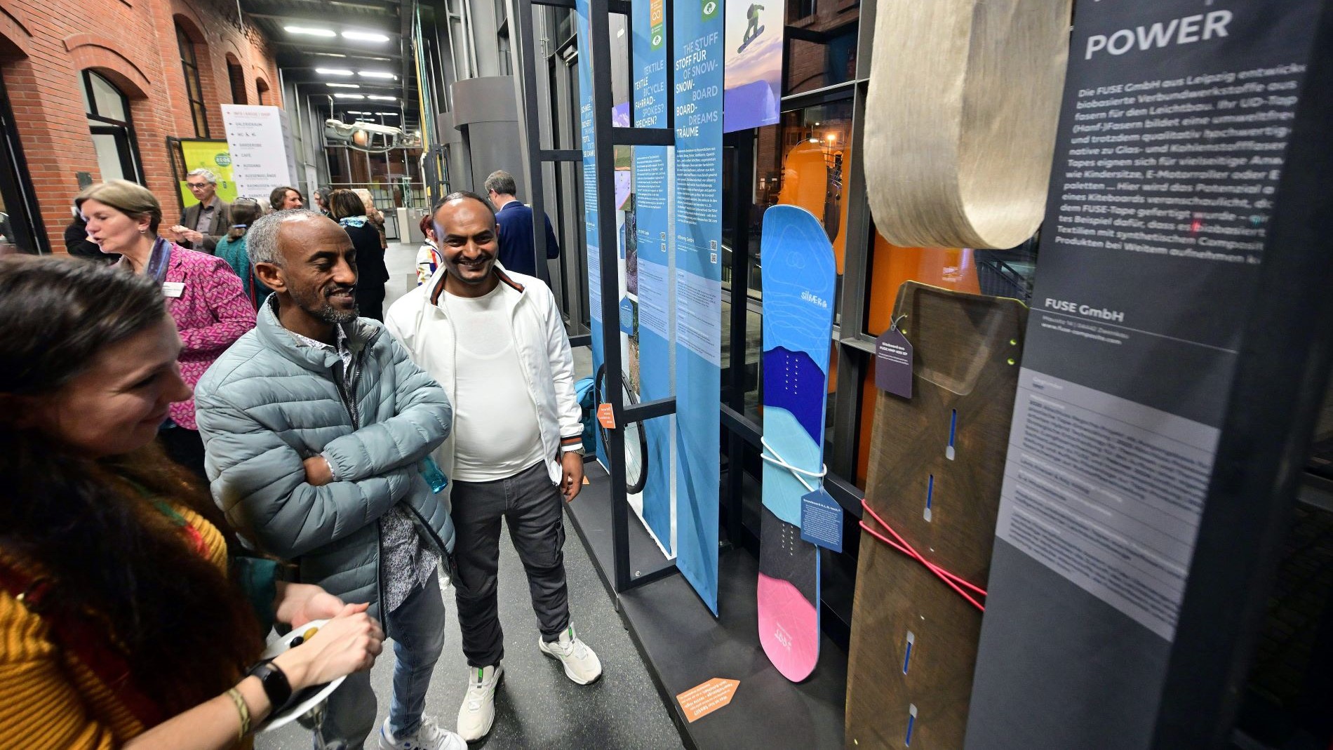 Besucherinnen und Besucher einer Ausstellung zur Textilindustrie betrachten innovative Produkte aus nachhaltigen Verbundfasern.