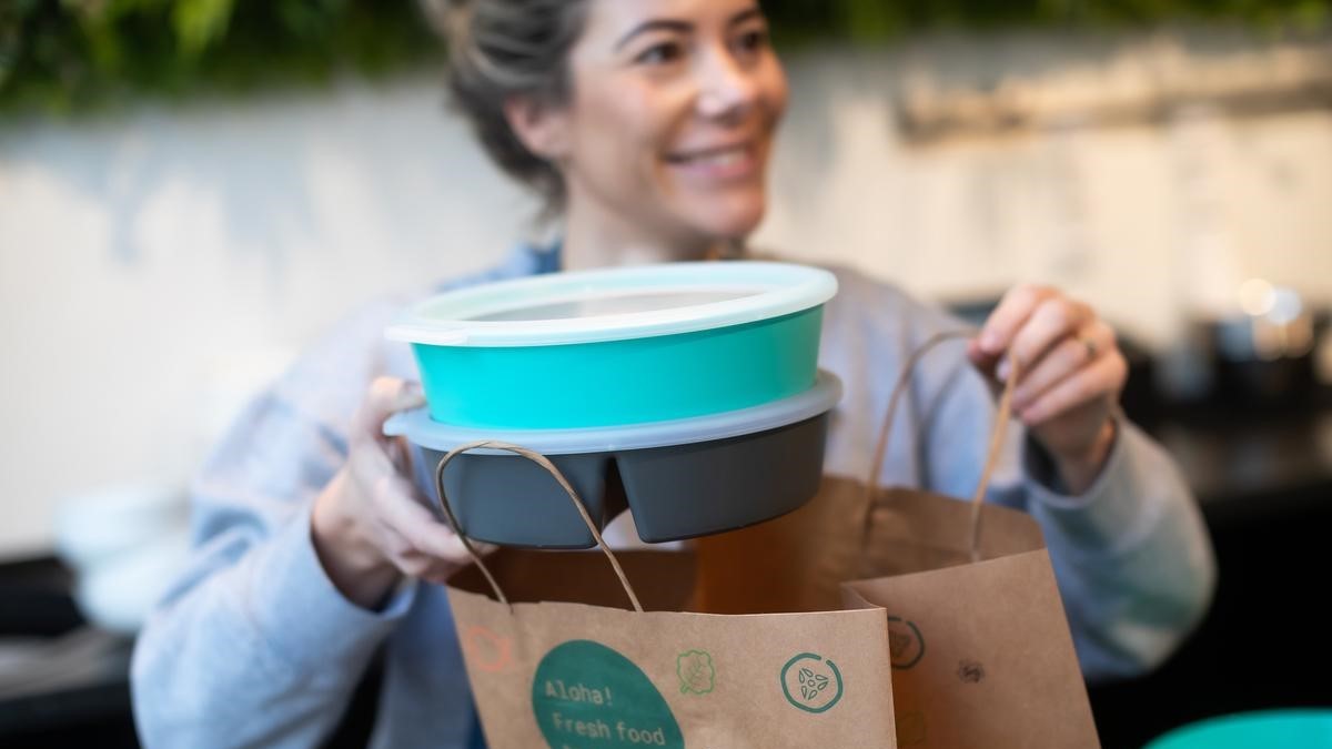 Woman picks up recyclable crockery from a delivery service's paper bag