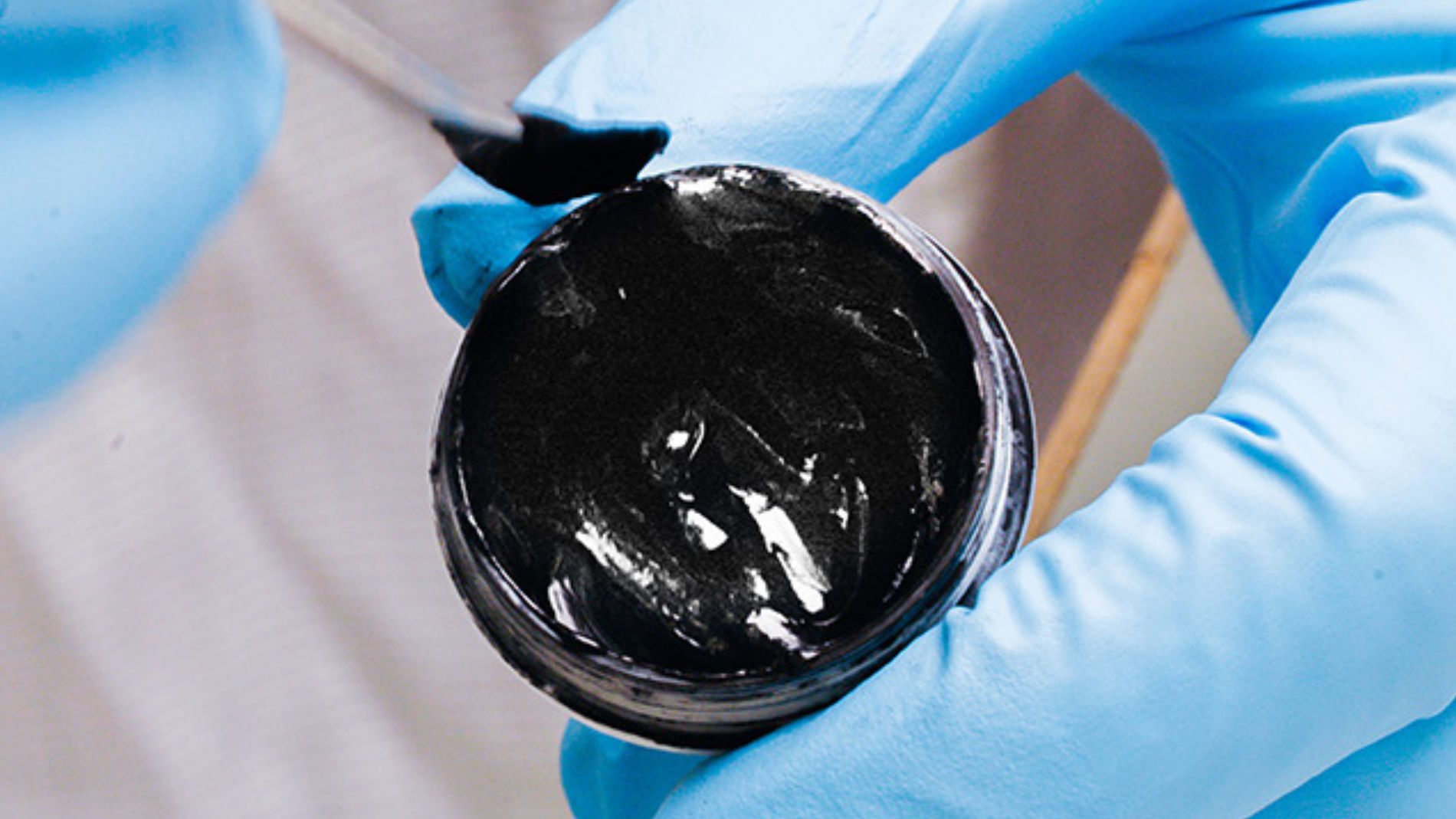 Nahaufnahme von schwarzem Material für flexible Batterie in blauen Schutzhandschuhen
