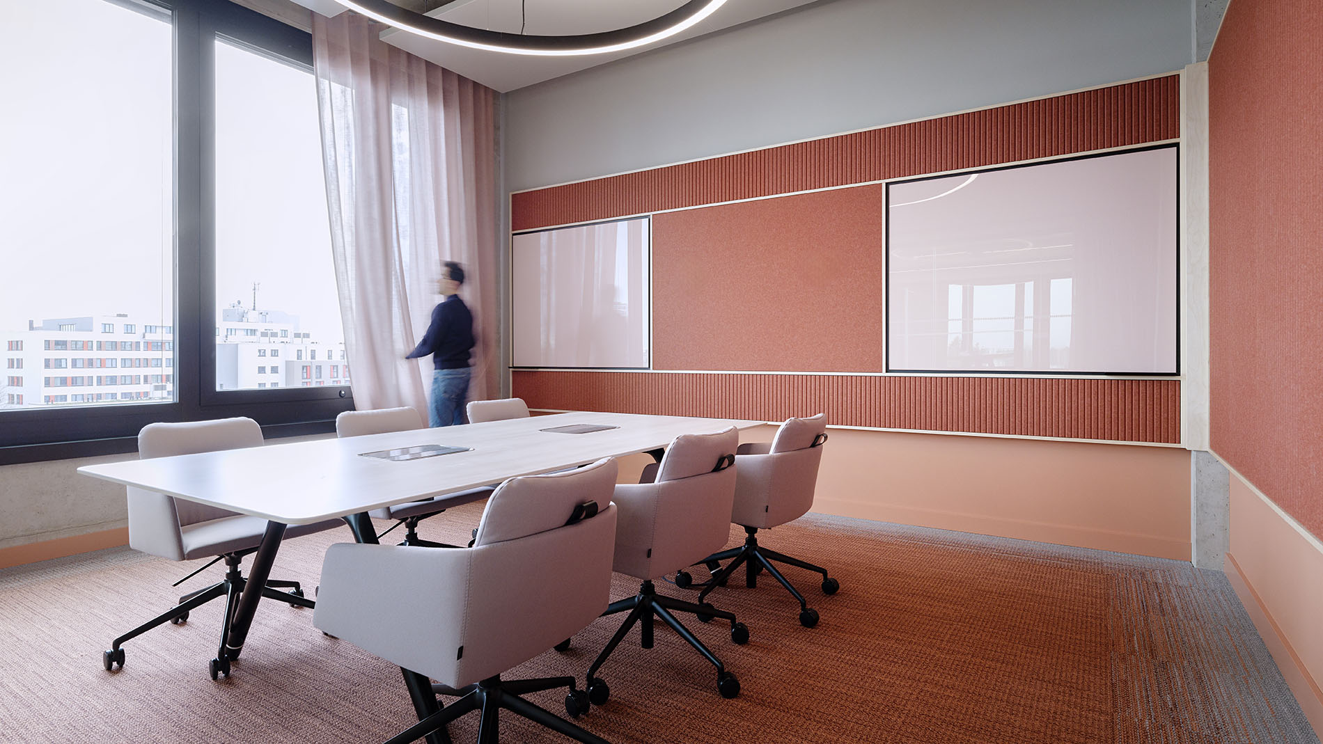Meeting room with large windows, soft pink walls, and acoustic curtains