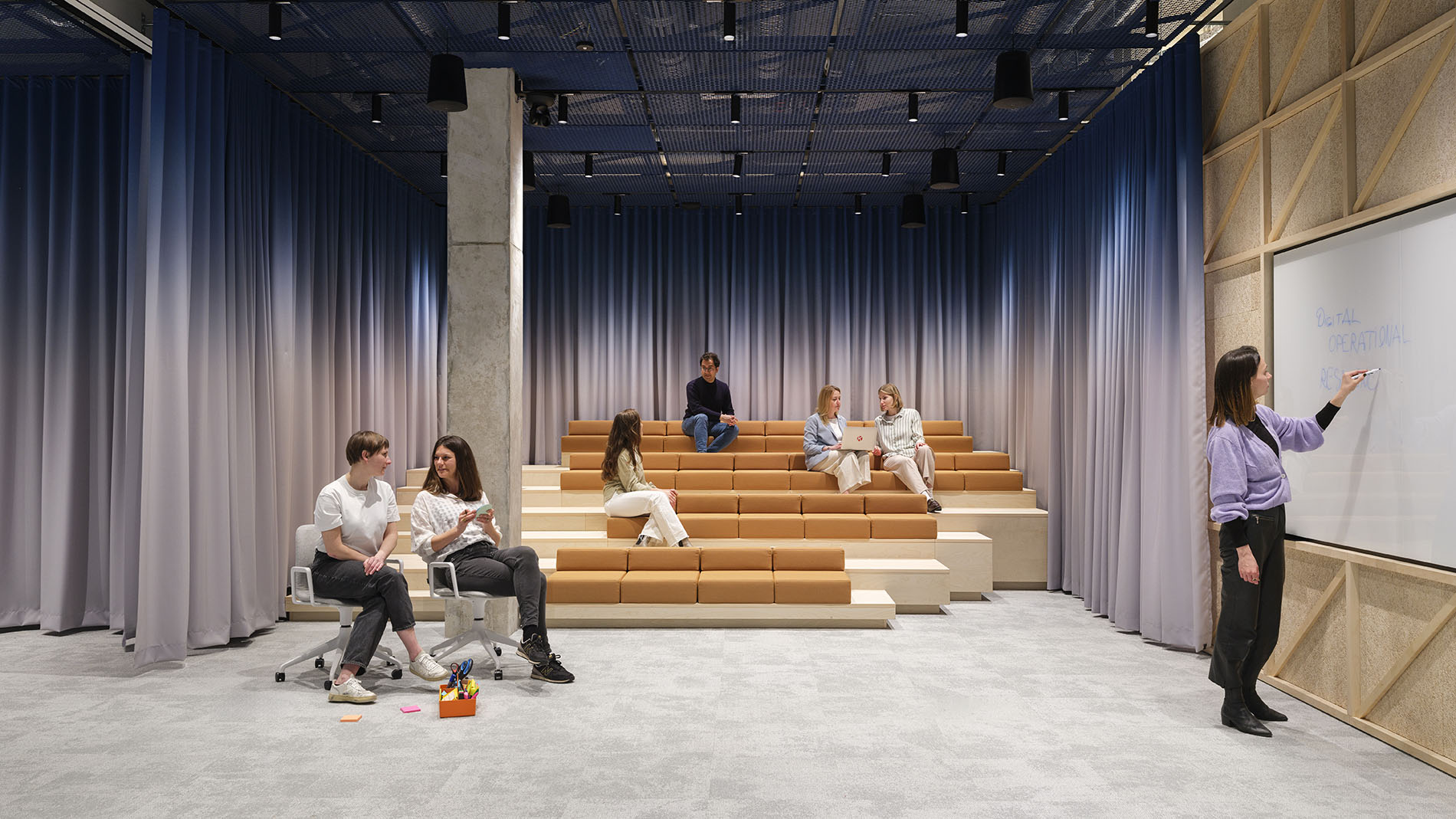 Presentation and workshop space with tiered seating and blue-grey curtains