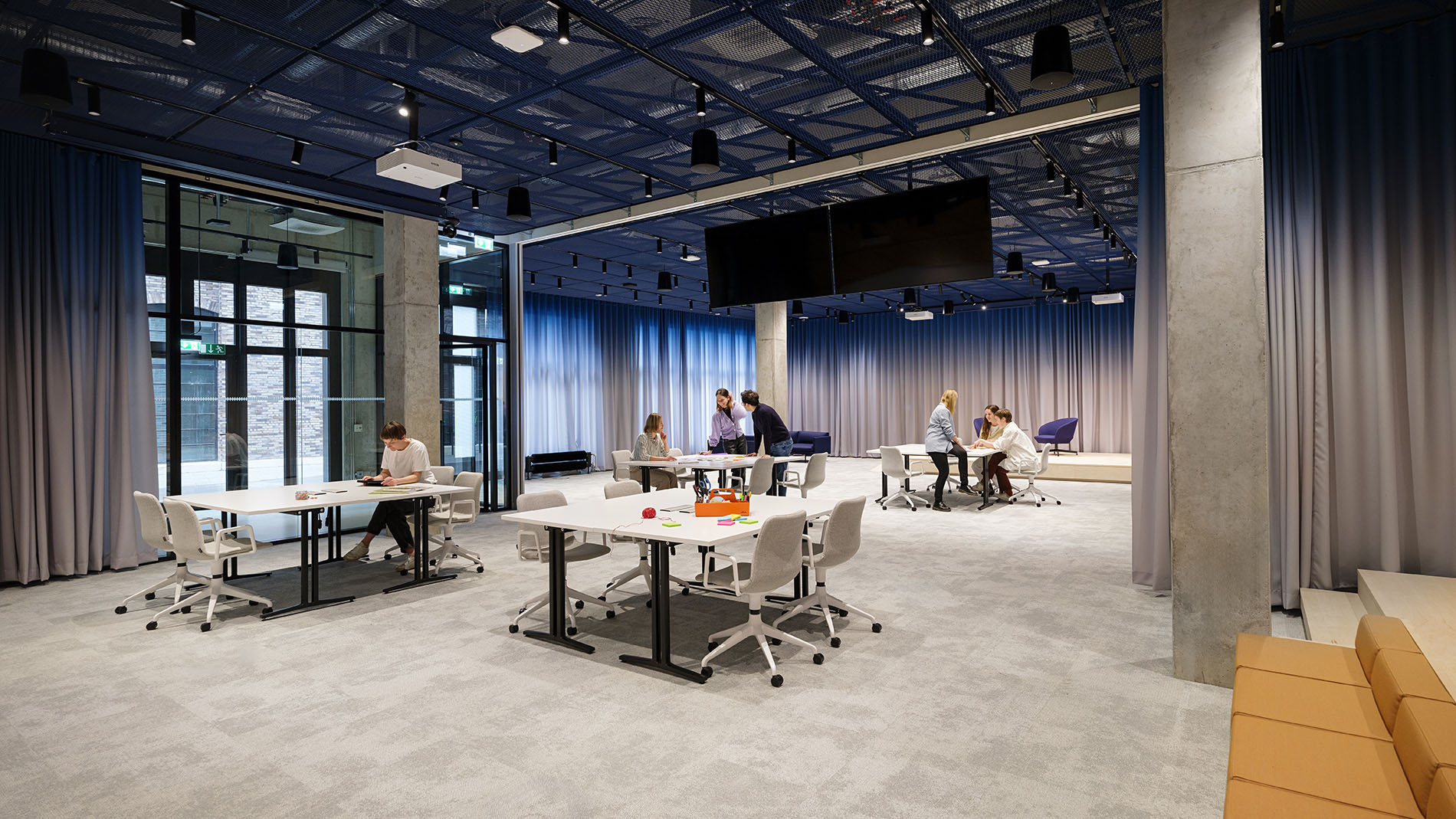 Spacious co-working area with flexible desks, modern office chairs, and textile acoustic elements