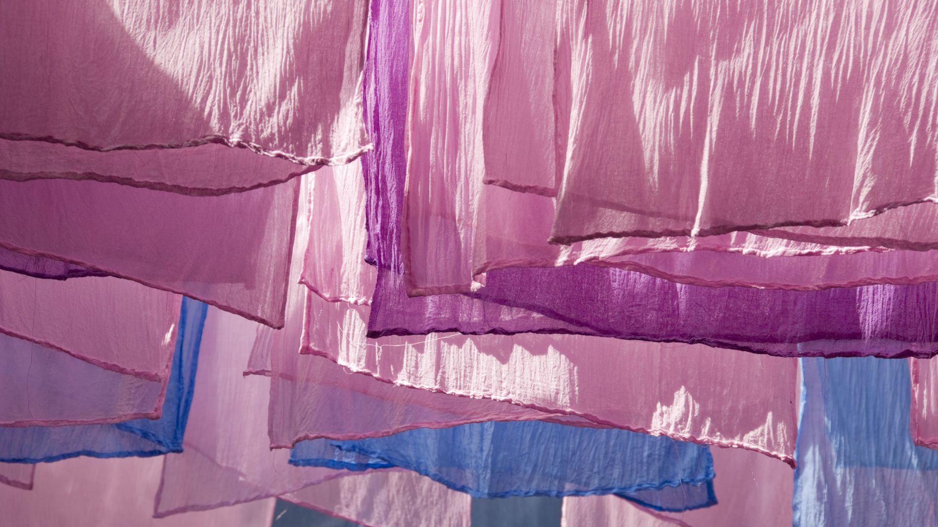 Colourful fabrics in shades of pink and purple hanging to dry