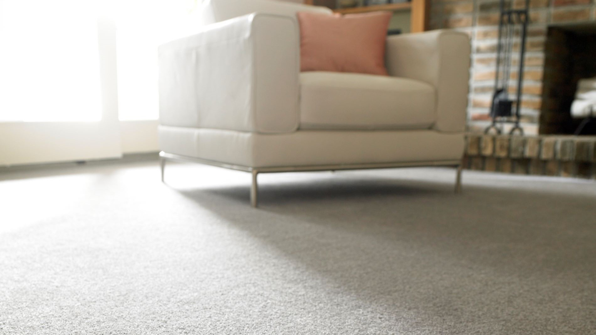 White armchair with cushions stands on a rug in front of a fireplace