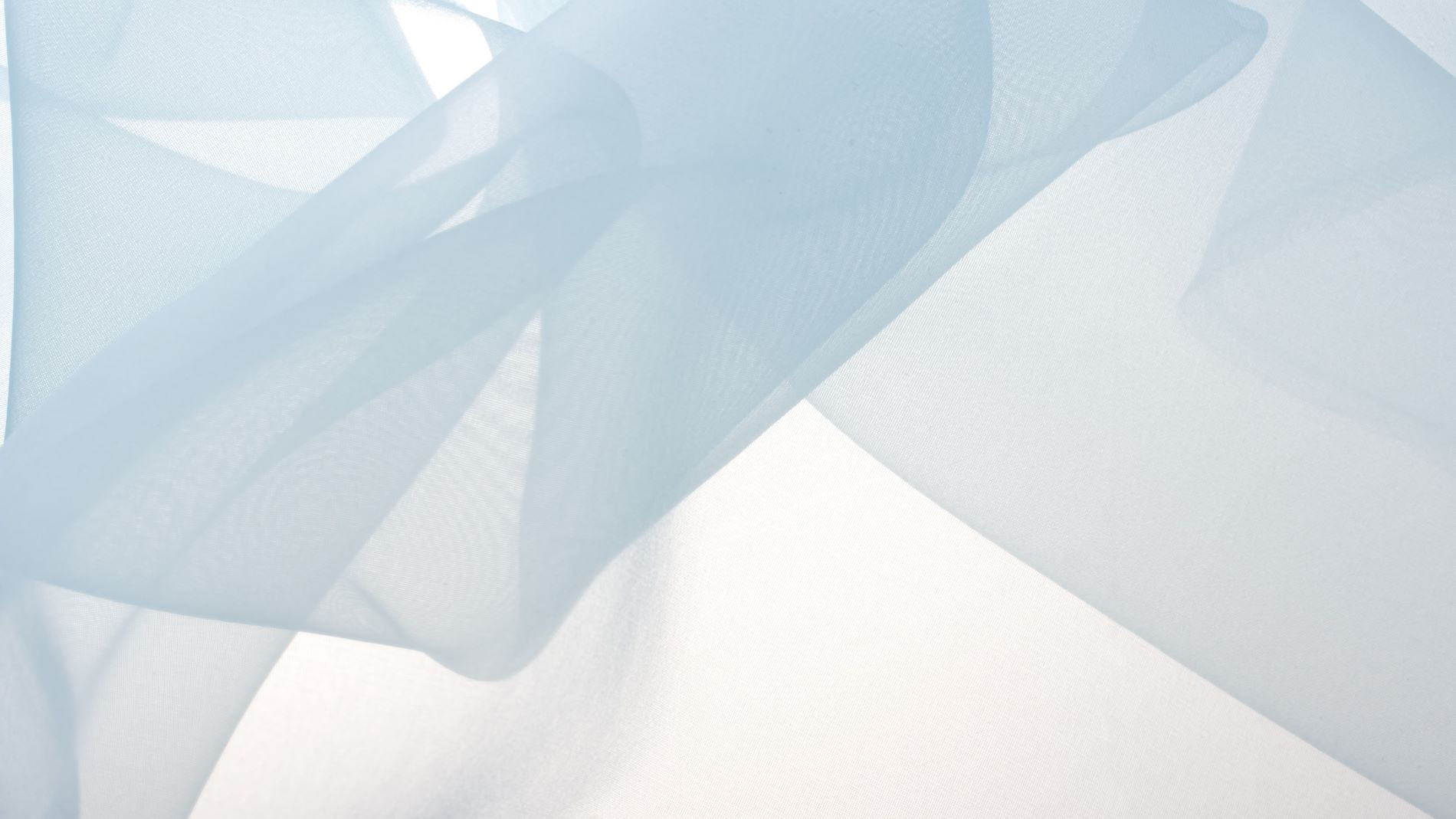 Zarte, hellblaue transparente Stoffschichten, die sanft übereinanderliegen