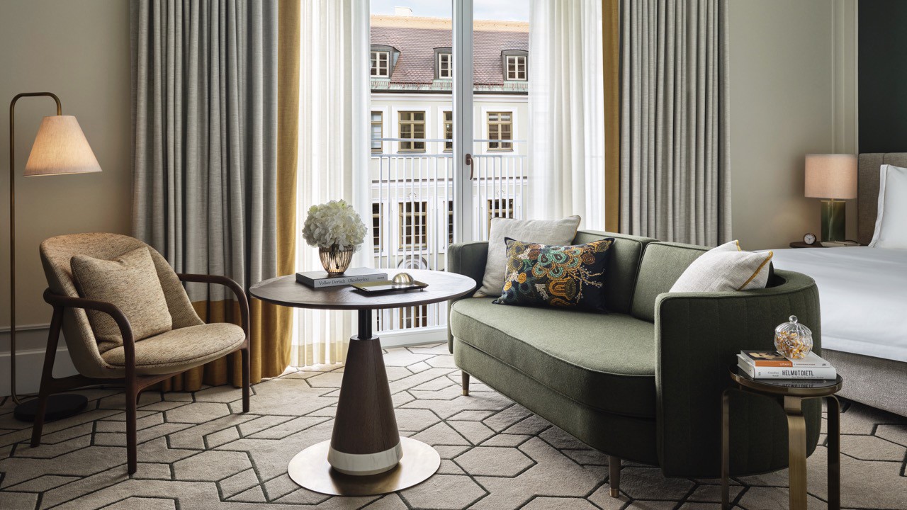 Bright bedroom with cosy seating area and balcony view.