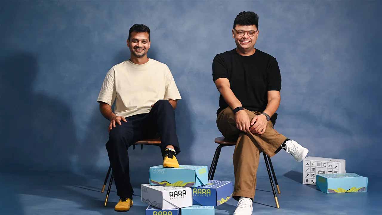 Two founders sit among colourful product boxes.