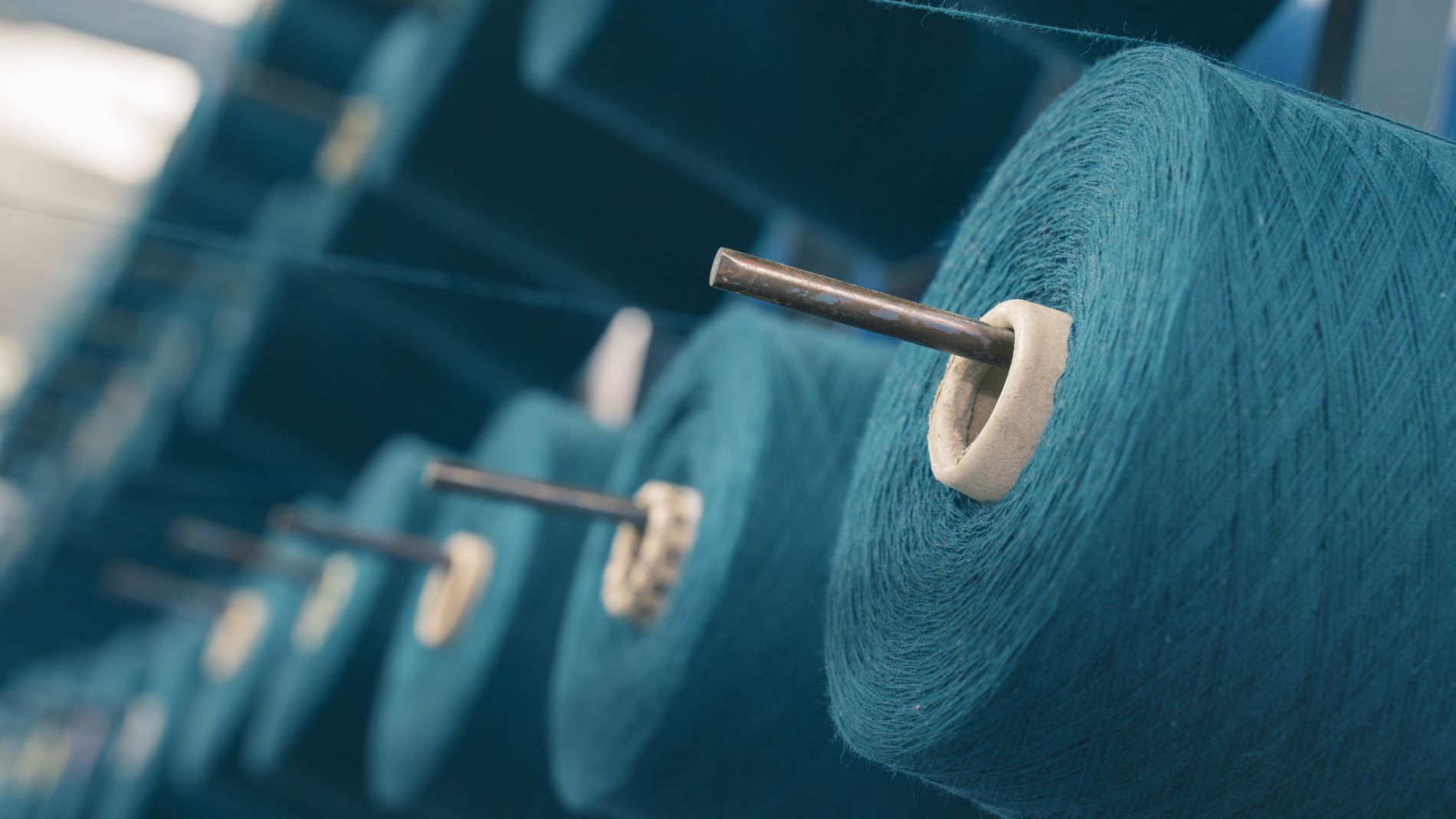 Close-up of large, turquoise-coloured spools of thread.