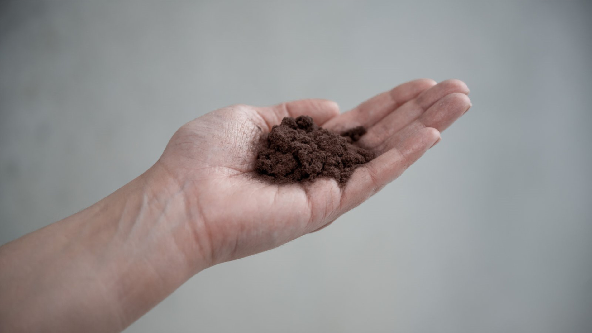 Dark recycled material resting on palm