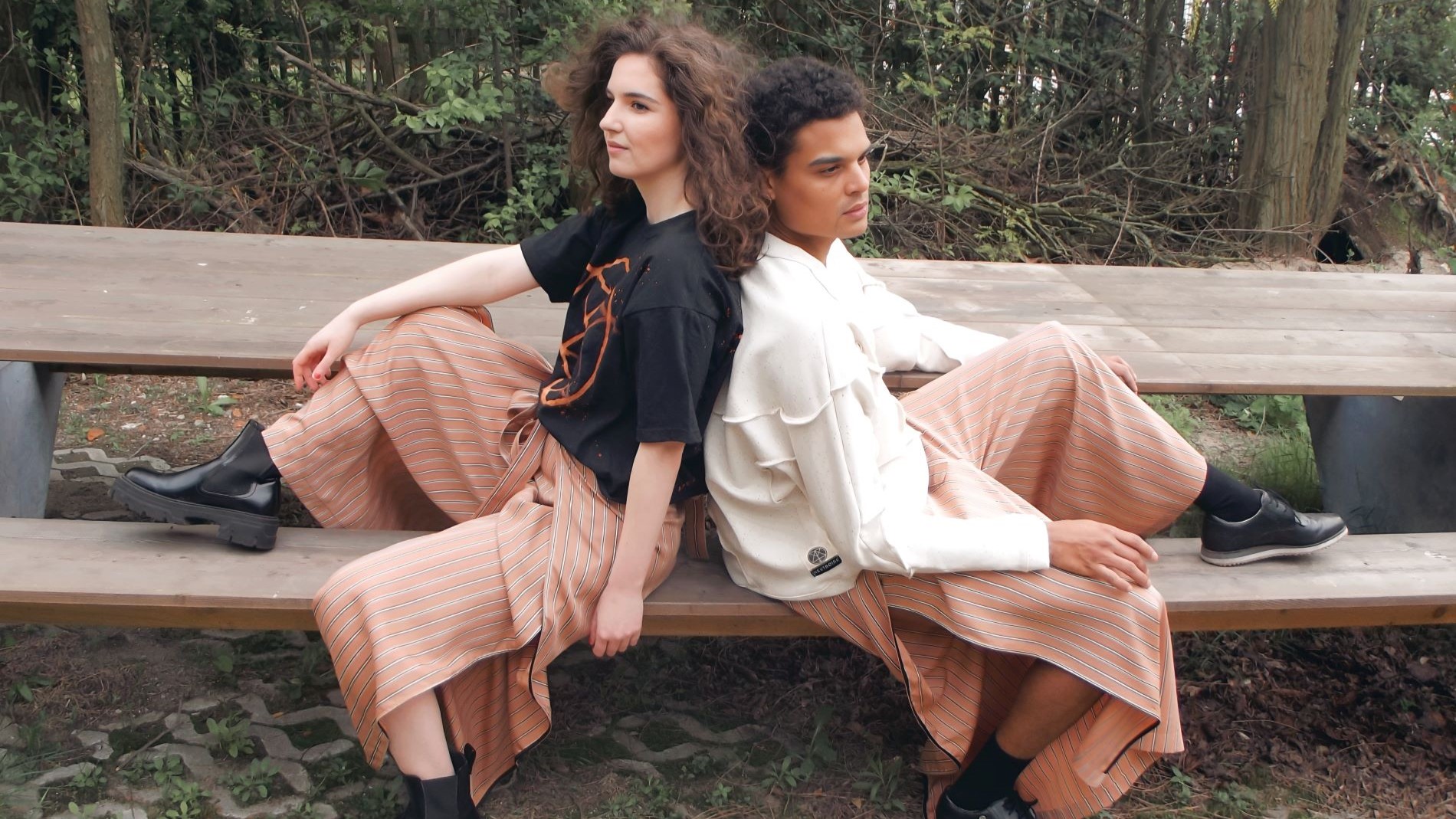 Two models sitting back to back casually