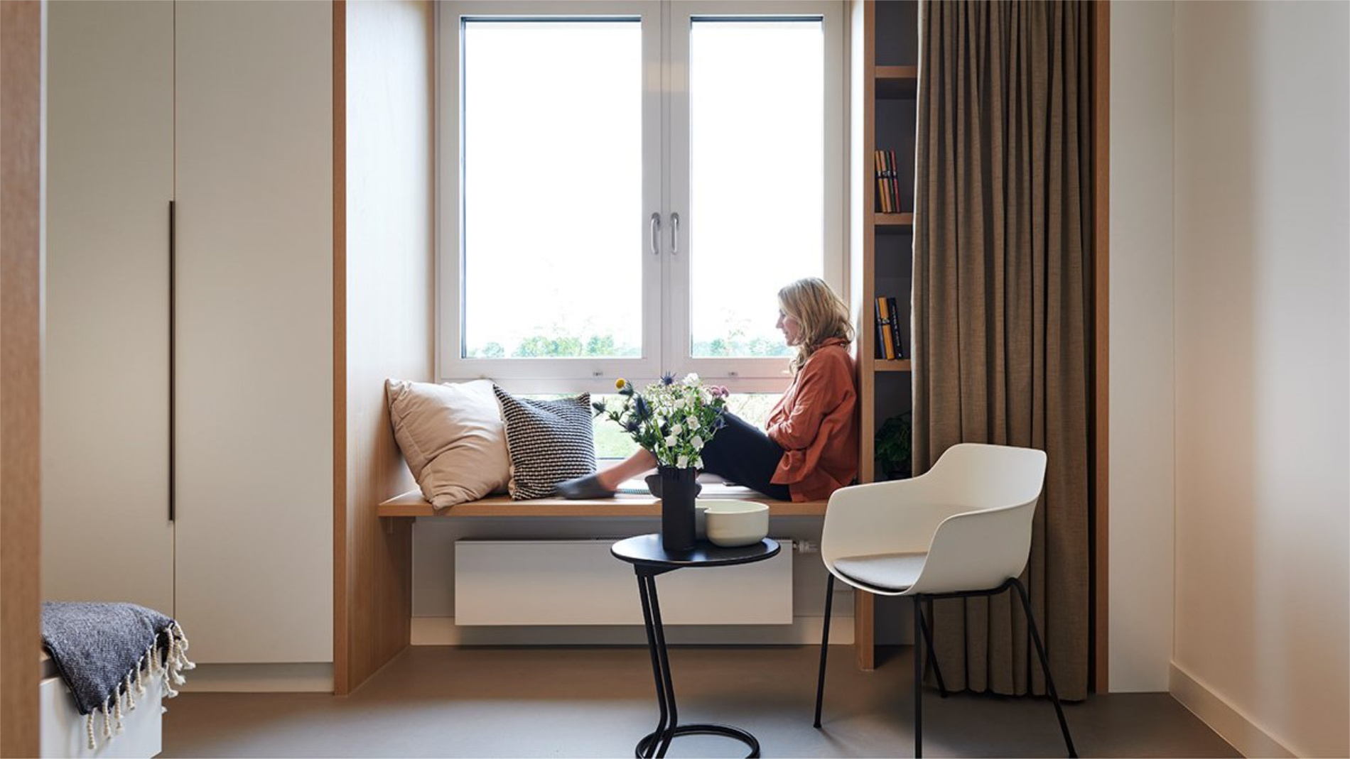 Woman is sitting on abench next to the window