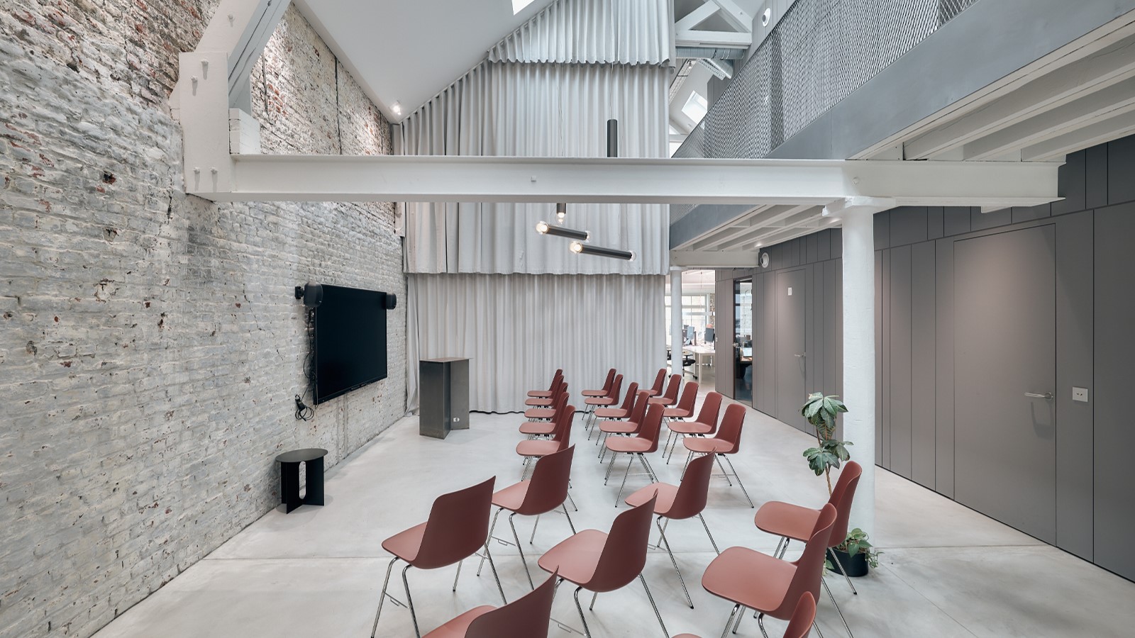 Präsentationsraum mit Stuhlreihen und Backsteinwand