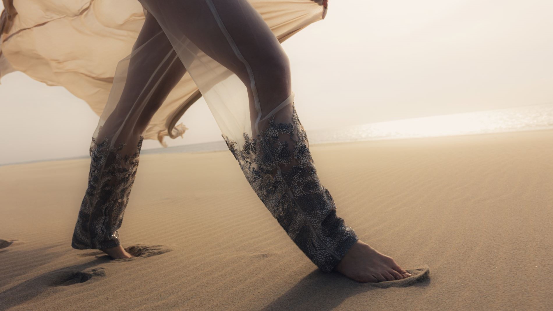 Barefoot in the sand with transparent designer trousers