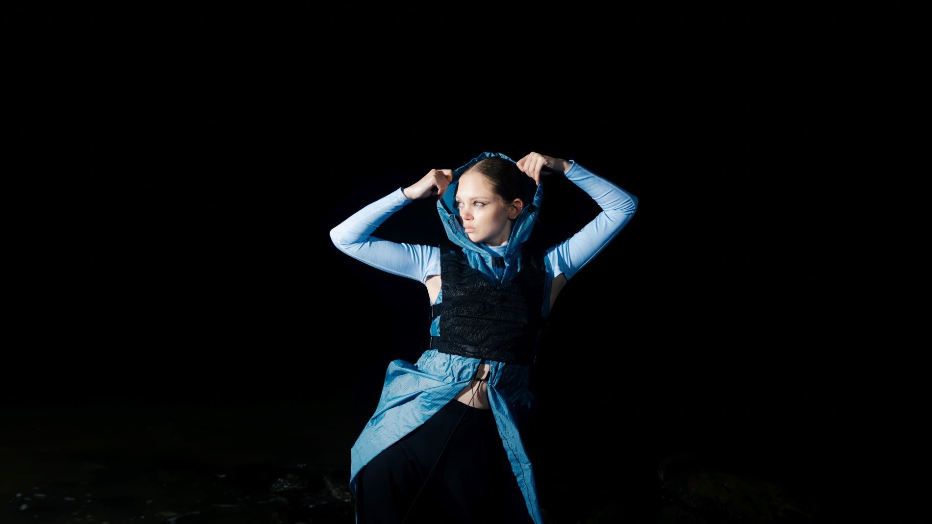 Model with blue hoodie in front of black background