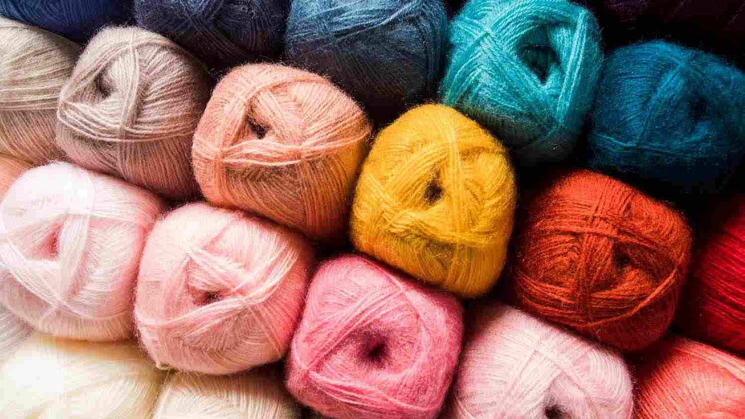 Stacked colourful yarn balls in various shades.